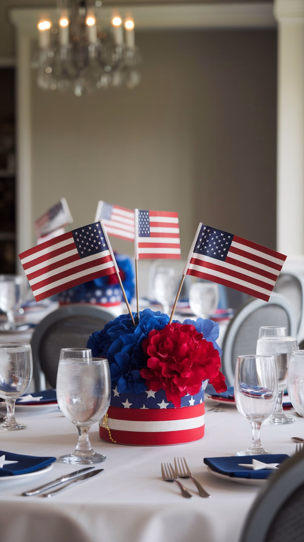 A festive table centerpiece featuring red and blue flowers with small American flags for a 4th of July party.