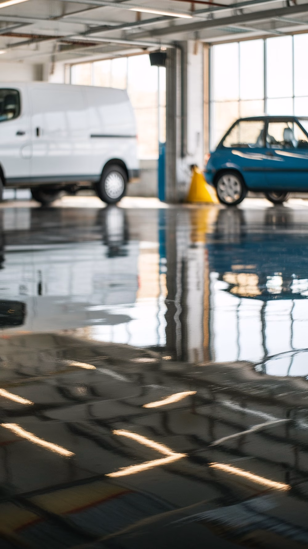 A polished concrete garage floor reflecting light with two parked cars